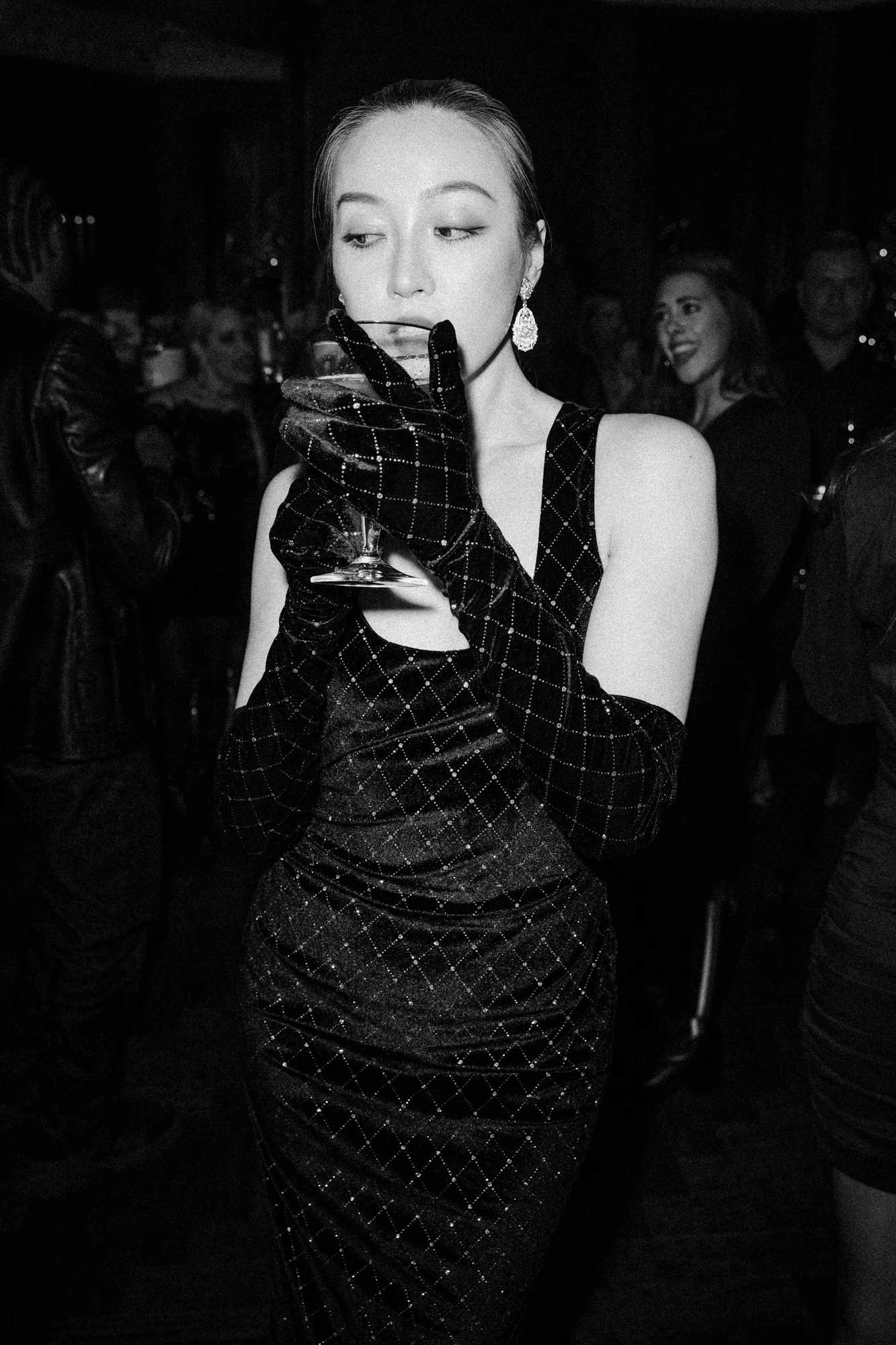 Black and white portrait of a woman in a sequined gown holding a champagne glass