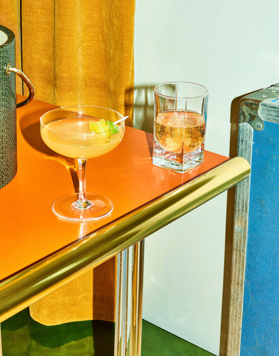 Cocktail and whisky glasses on a vivid orange table