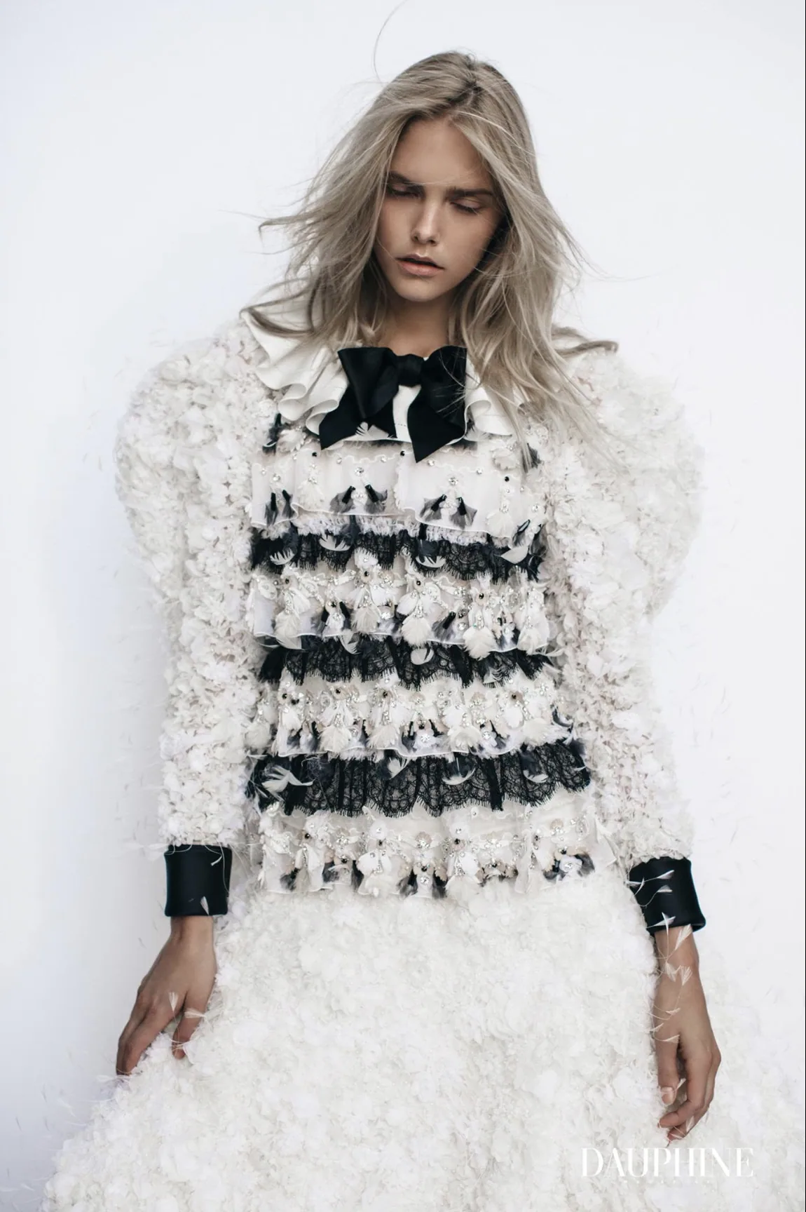 Model in a white feathered and lace couture look with a black silk bow