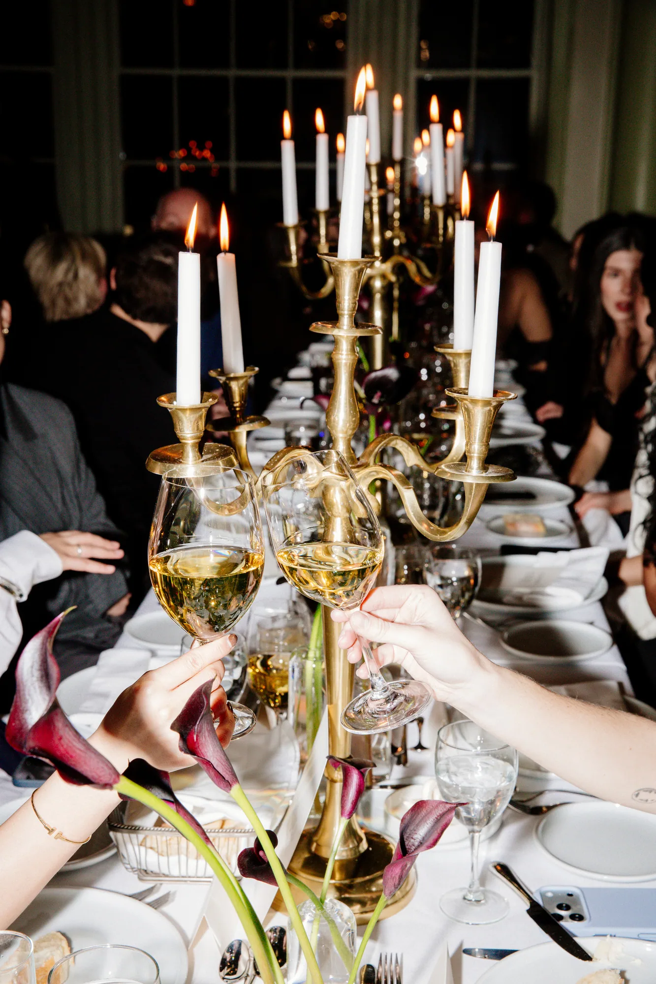 Guests dining around a candlelit table with a brass candelabra
