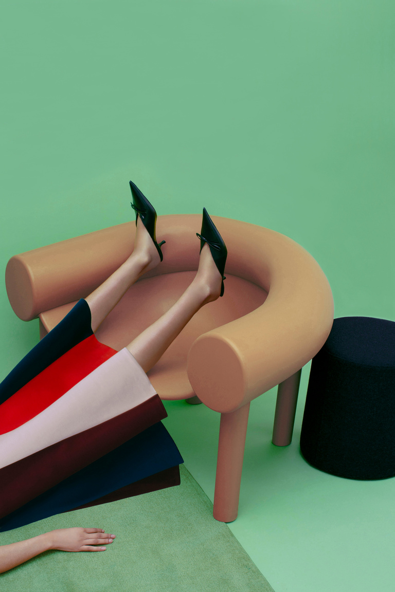 Reclining figure in a colour-block skirt on sculptural seating