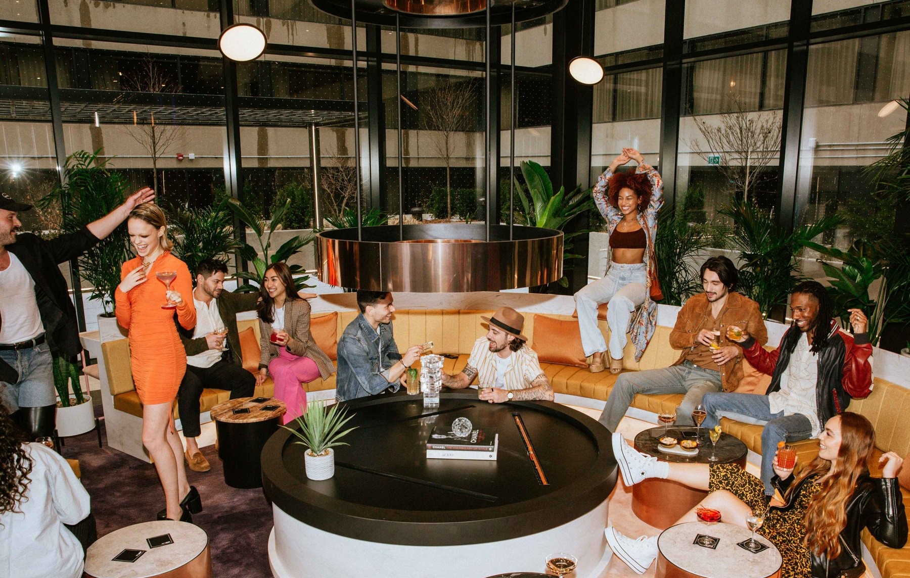 Guests mingling around a circular fireplace in a hotel lounge