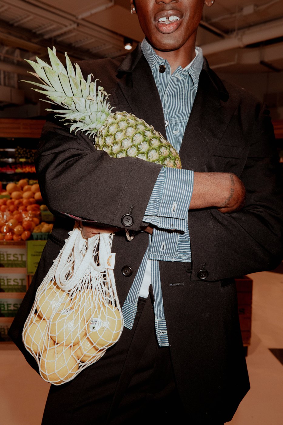 Model with a pineapple and mesh bag of lemons