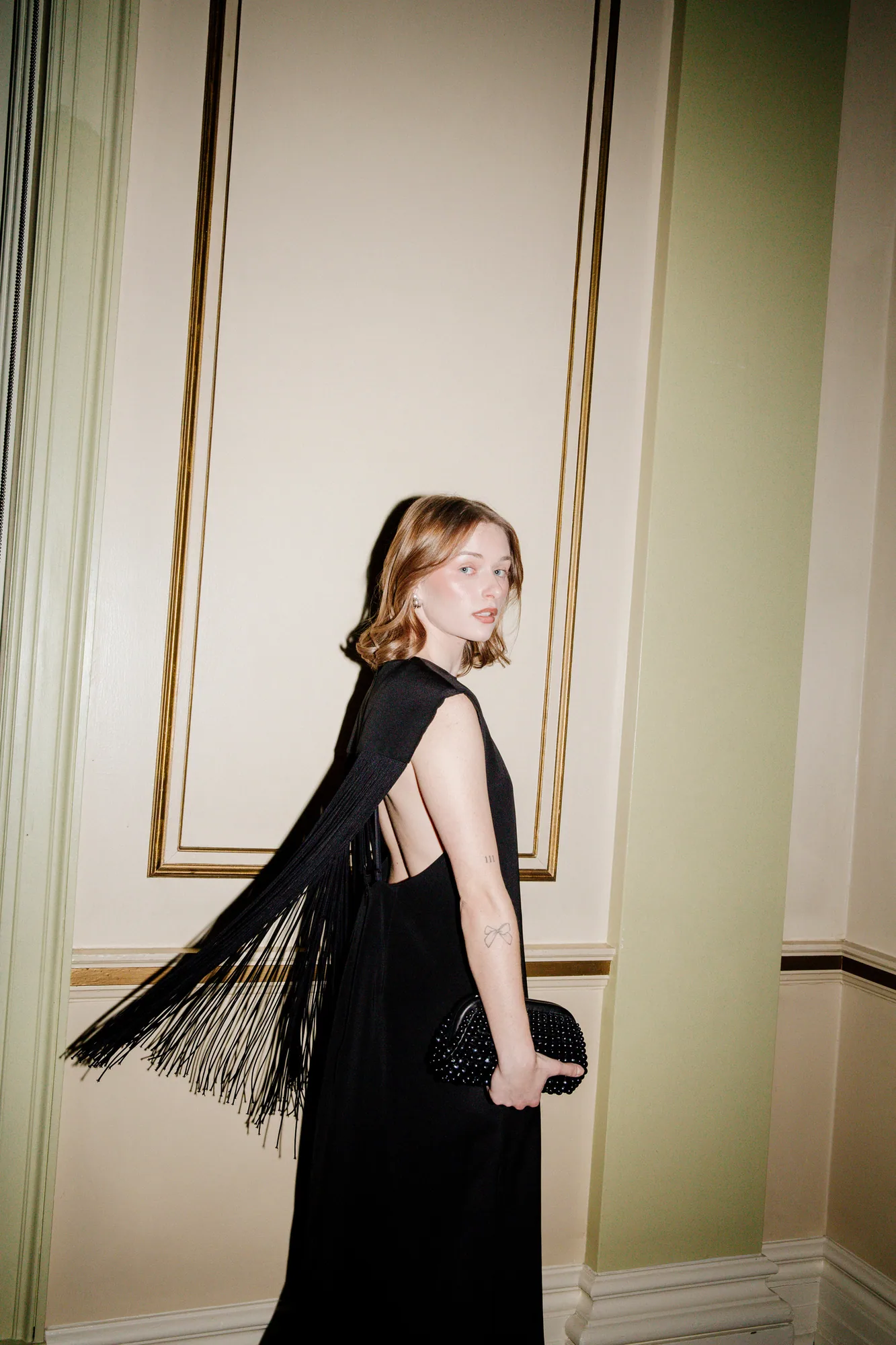 Woman in a black fringed gown in a panelled room