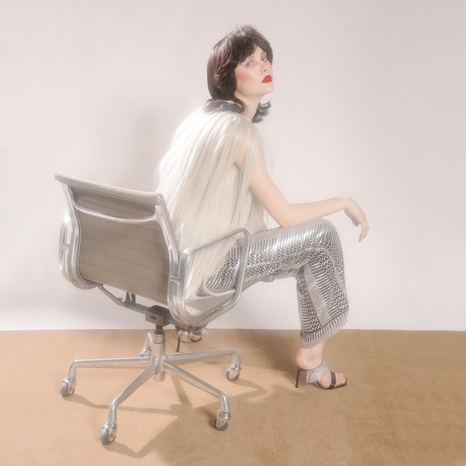 Model in sequined trousers seated in an office chair