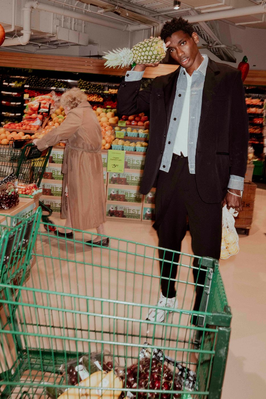 Model holding a pineapple in a grocery store