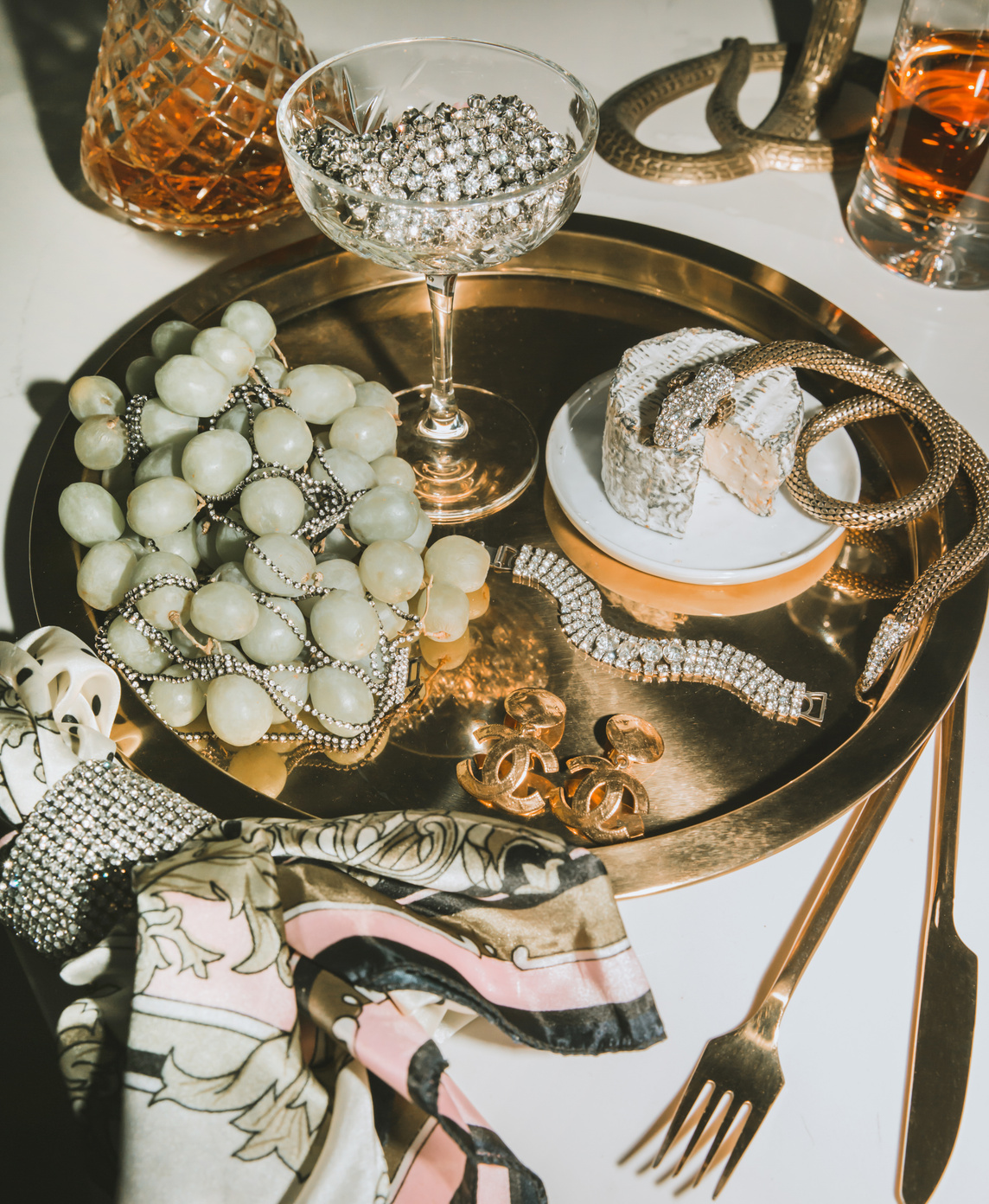 Jewellery, pearls, cheese and grapes arranged on a gold tray