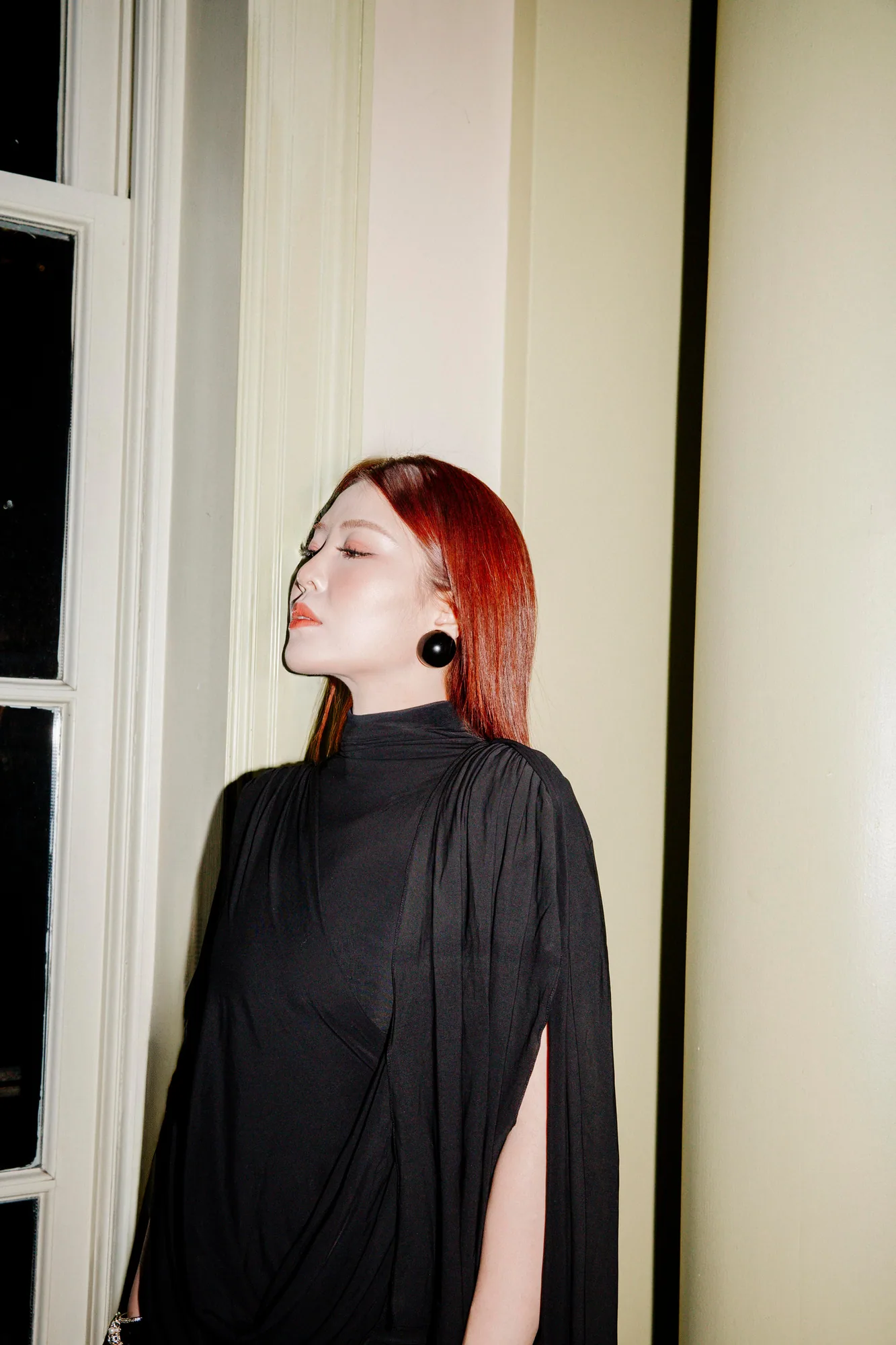Profile of a red-haired woman in a black high-neck gown