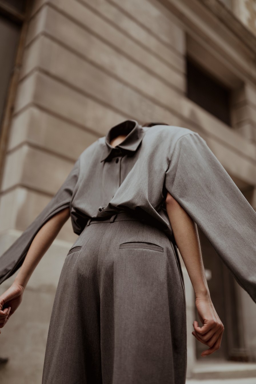 Model in a grey dress against a stone facade