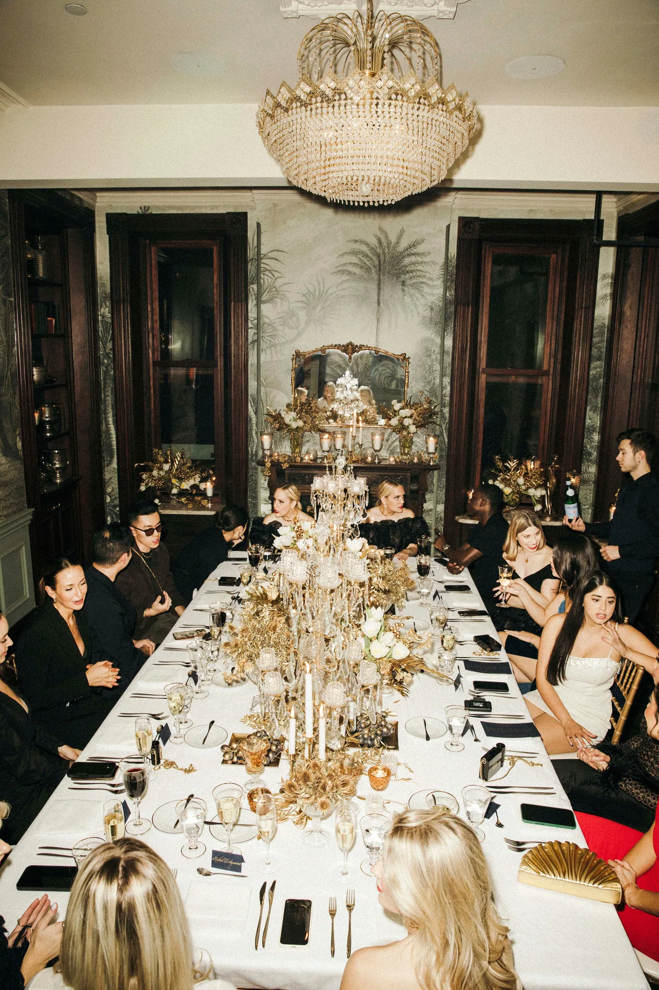 Guests dining at a long table beneath a chandelier
