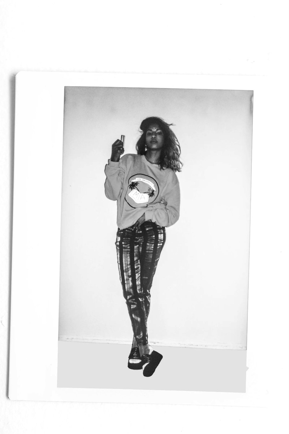 M.I.A. posing in a sweatshirt and patterned trousers