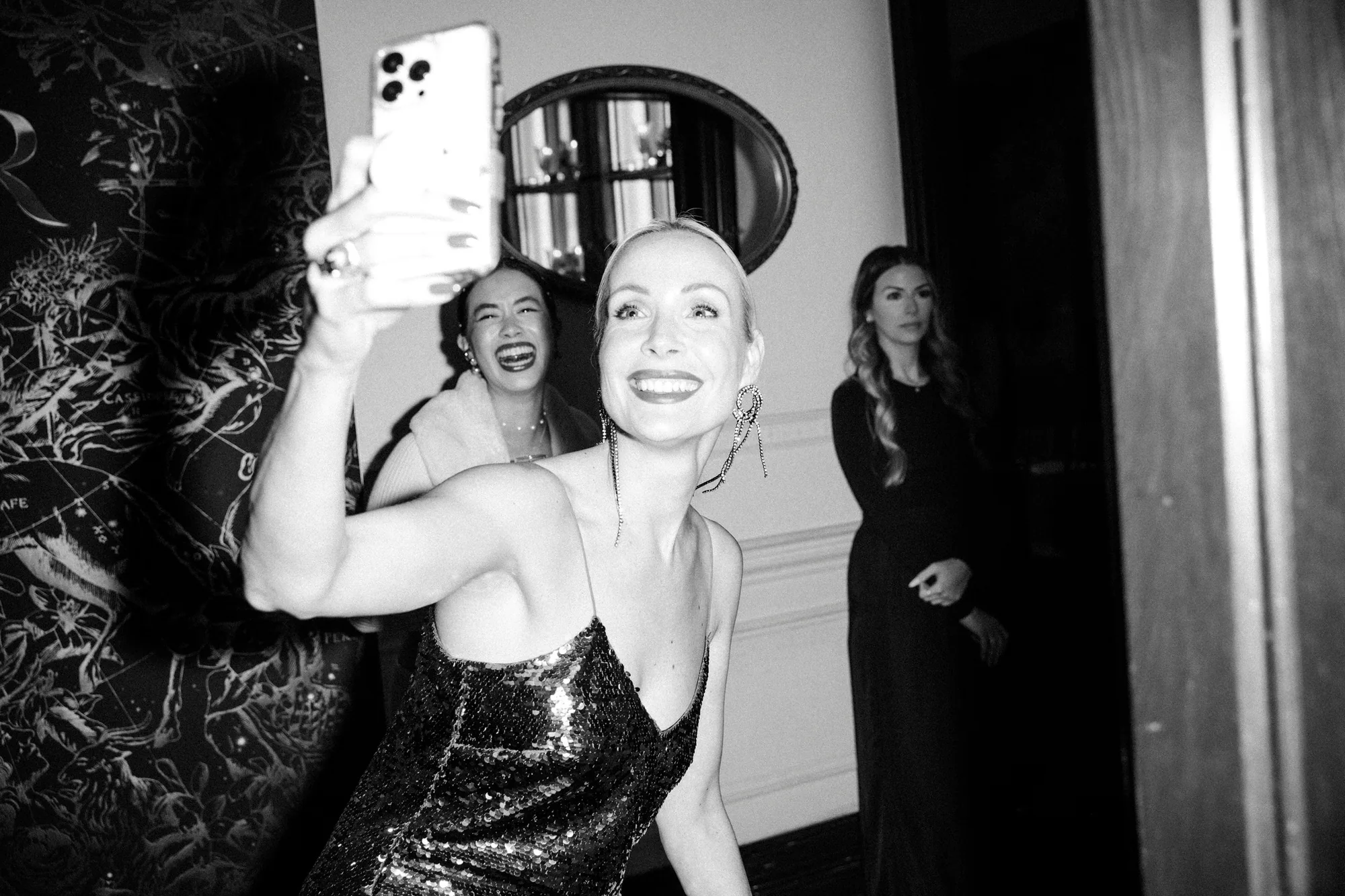 Black and white shot of a woman taking a selfie at the party