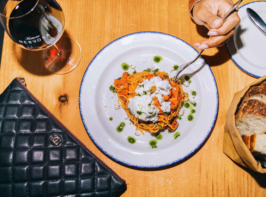 Burrata pasta and wine beside a black quilted clutch