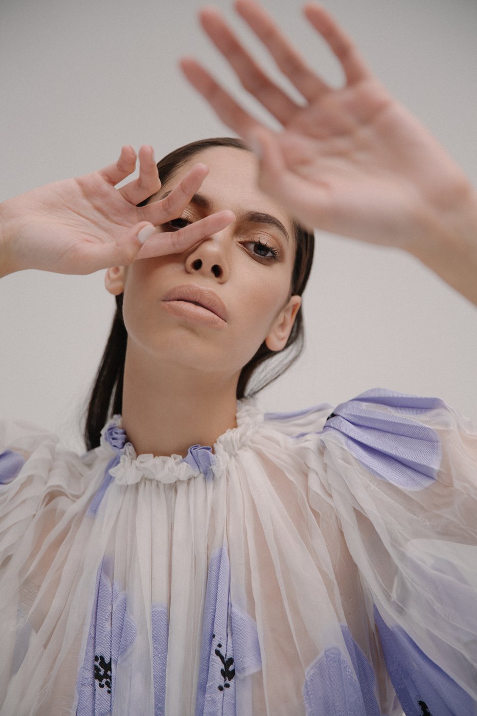 Model in a lavender ruffled top with hands raised