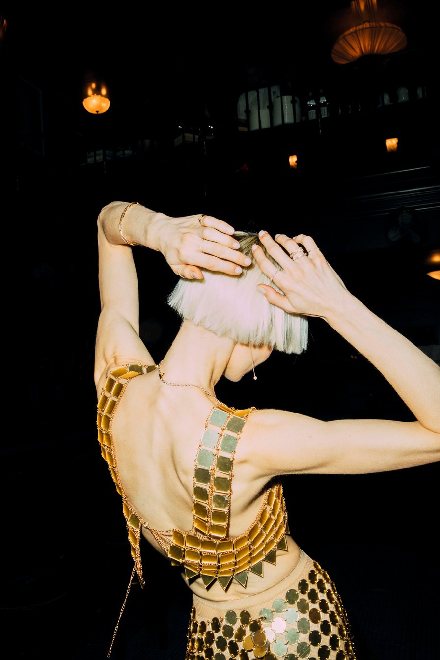 Model with arms raised in a gold sequinned dress