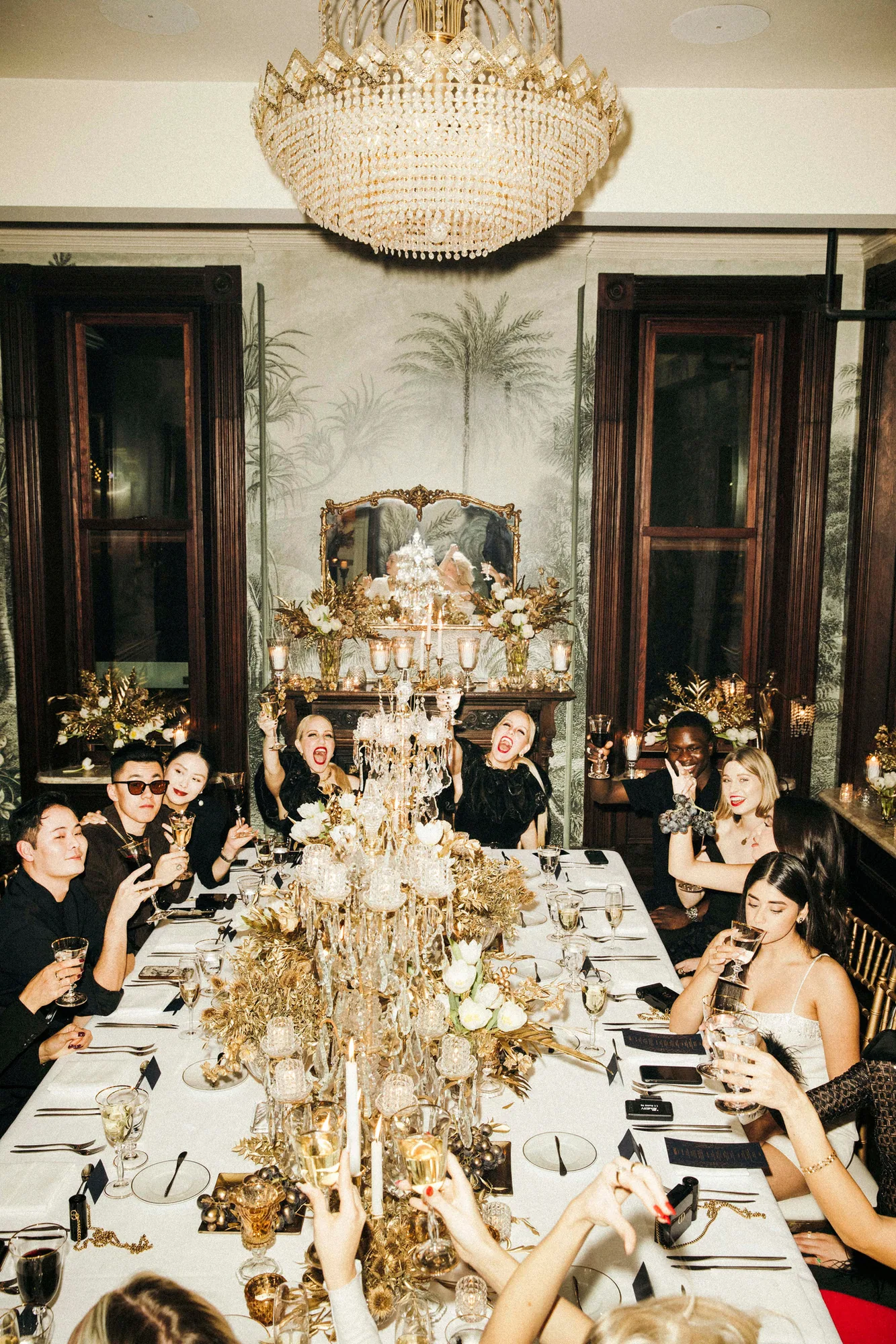 Guests at a long banquet table beneath a crystal chandelier
