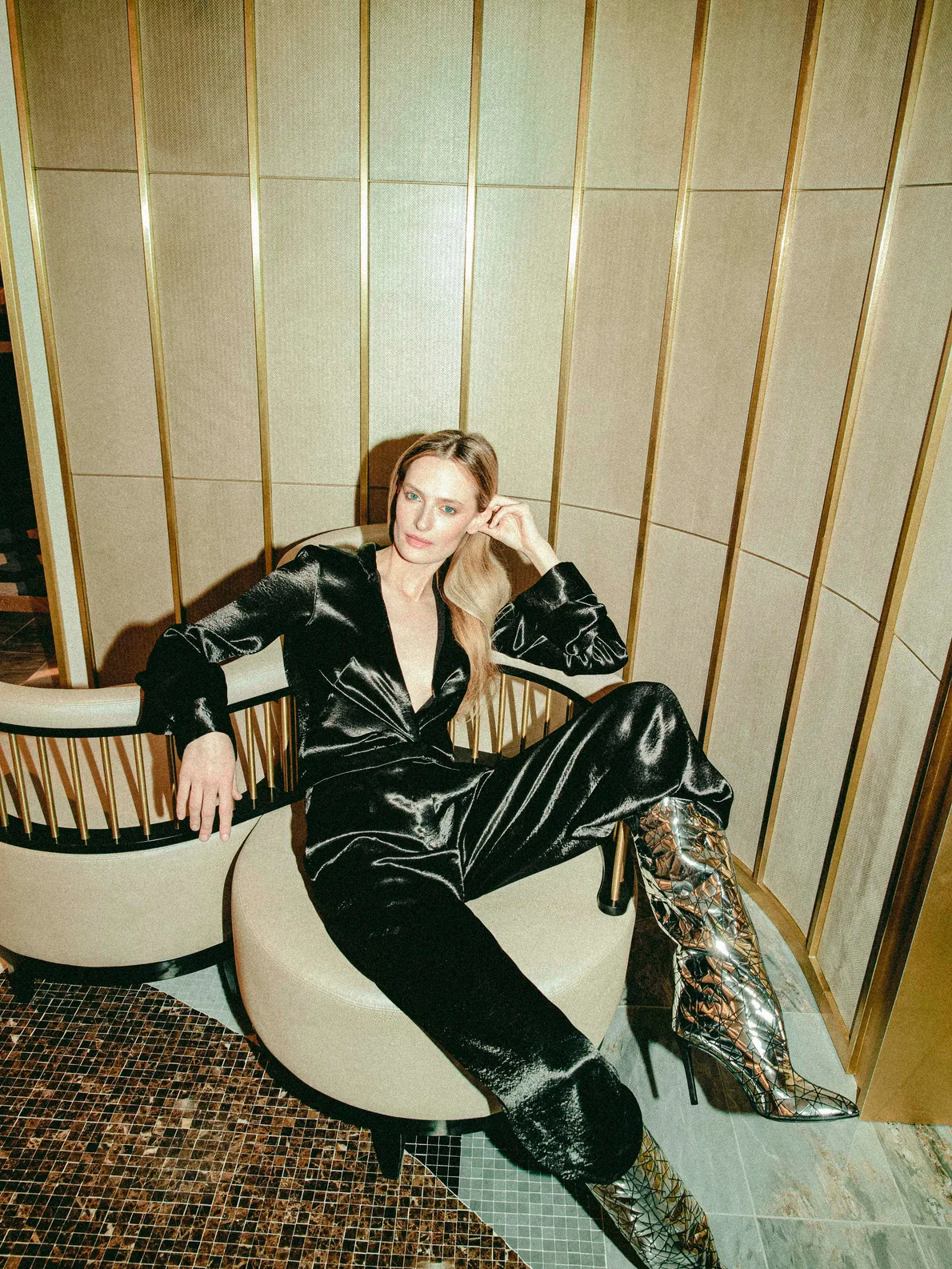 Woman in a dark green velvet suit seated in a gold-panelled room